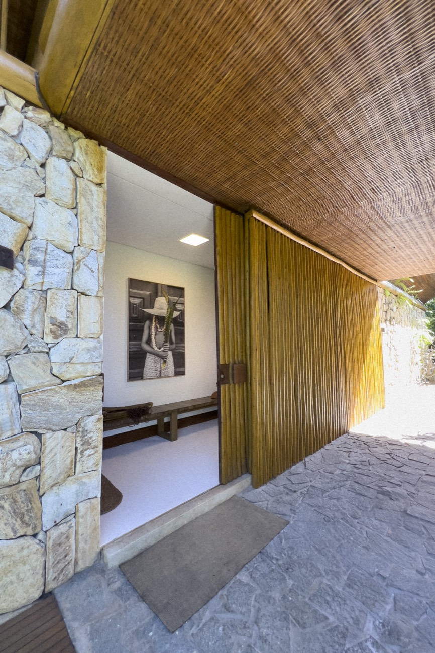 Entrada em pedra e madeira da Casa Tortuga, com parede de pedra natural e forro de fibra