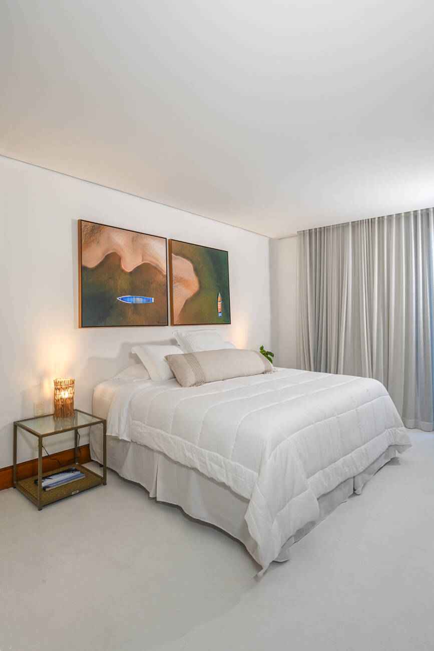 Quarto com par de obras de barcos e cortina translúcida